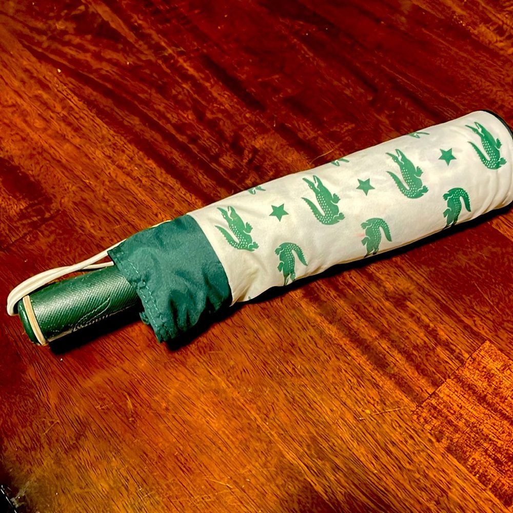 Vintage Lacoste collapsing umbrella with swirl Lacoste logo. Has matching cover